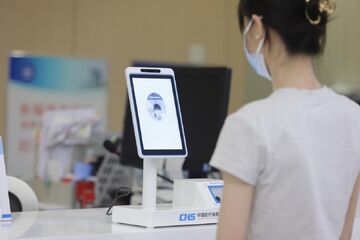 手持身份证进行人脸识别认证的示意图,旁边有手机和电脑,强调安全合规,关键词“比特币怎么开户”