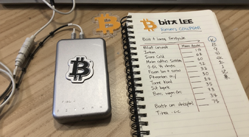 比特币冷钱包硬件设备照片,旁边放着比特小鹿挖矿收益记录本,关键词比特币