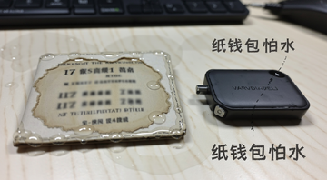 一张被水泡过的纸钱包,字迹模糊,旁边放着一个硬件钱包做对比,背景是桌面,文字注明“纸钱包怕水”